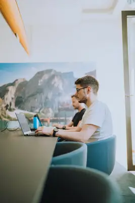 Zwei Kollegen sitzen mit Laptop am Konferenztisch.