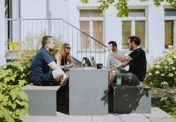 Drei Kollegen und eine Kollegin haben ein Meeting im Freien.