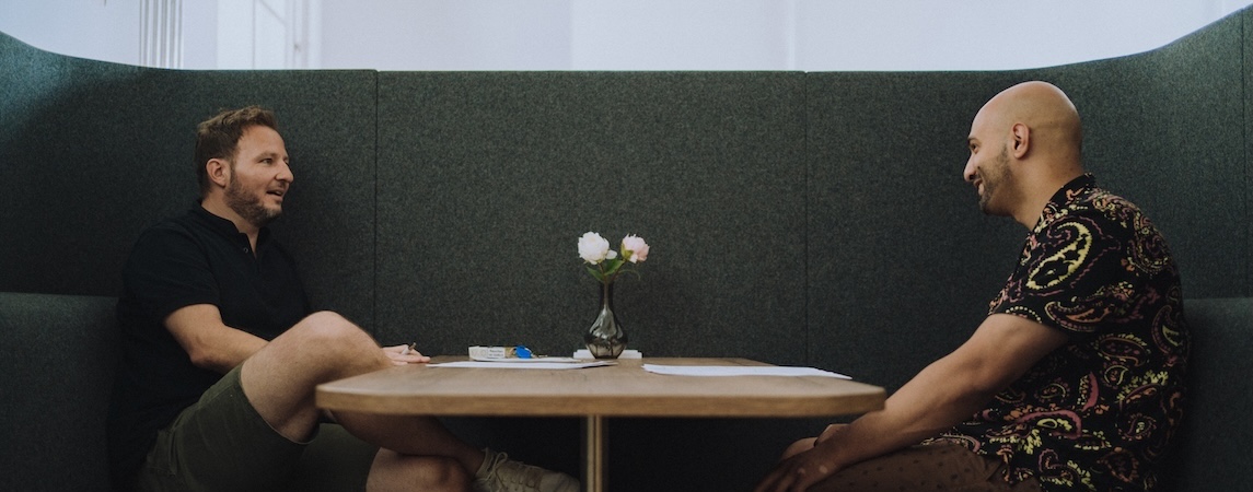 Kollege und Kollegin unterhalten sich in einer Meeting-Box.